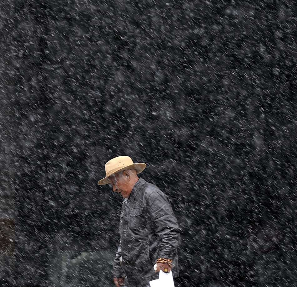 An old man walks in snow in Lhasa, capital of southwest China's Tibet Autonomous Region, March 11, 2013. (Xinhua/Purbu Zhaxi)