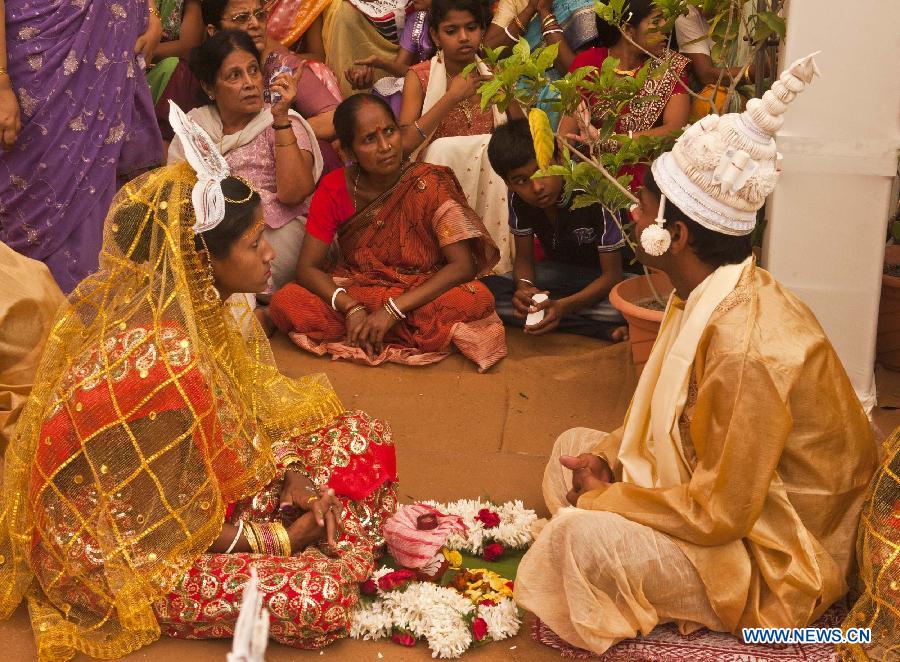 Indian bride and groom wait for a mass marriage ceremony in Calcutta, capital of eastern Indian state West Bengal, March 17, 2013. A total of 51 couples got married in this occasion on Sunday. Mass marriages in India are organized by social organizations primarily to help the economically backward families who can't afford the high ceremony costs as well as the customary dowry and expensive gifts which are still prevalent in many communities. (Xinhua/Tumpa Mondal)