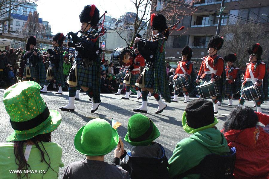 Spectators watch the annual St. Patrick's Day Parade in Vancouver, Canada, March 17, 2013. Thousands of people have crowded downtown Vancouver to watch as bagpipers, Irish dancers and hurlers paraded with dreadlocked dancers, green samba queens, and even a roller derby team took part in the 9th annual St. Patrick's Day parade. The festivities continue the centuries-old custom of partying on the saint's feast day, March 17, to honour his role of helping convert the Irish to the Catholic faith. (Xinhua/Sergei Bachlakov) 