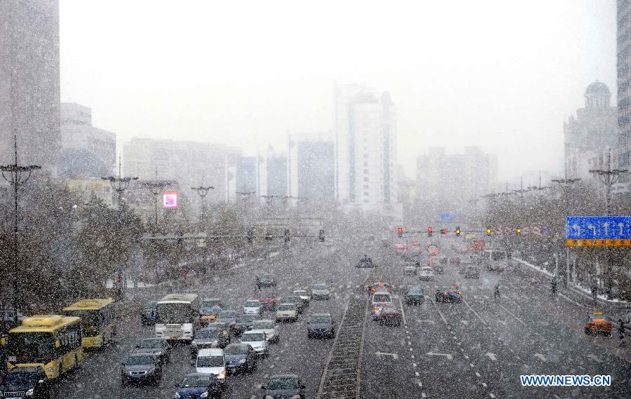 Motorcars run amid snowfall on a road in Harbin, capital of northeast China's Heilongjiang Province, March 18, 2013. A cold front brings snow and low temperature to Harbin on March 18. (Xinhua/Wang Song)  