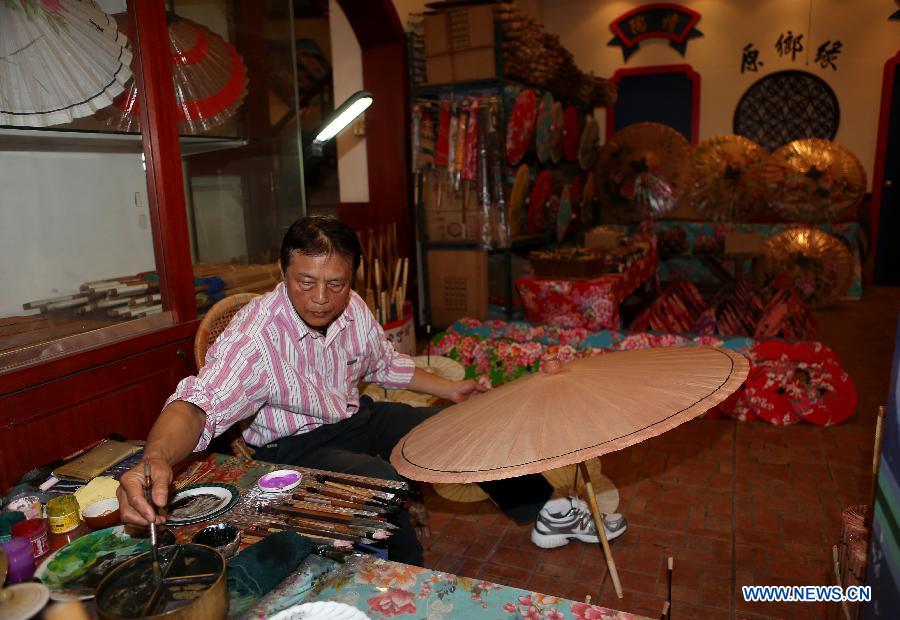 A man paints an oil paper umbrella in Yuanxiangyuan Village of Kaohsiung City in southeast China's Taiwan, March 18, 2013. The Yuanxiangyuan Village has attracted a good many tourists thanks to its burgeoning oil paper umbrella industry. (Xinhua/Xie Xiudong)