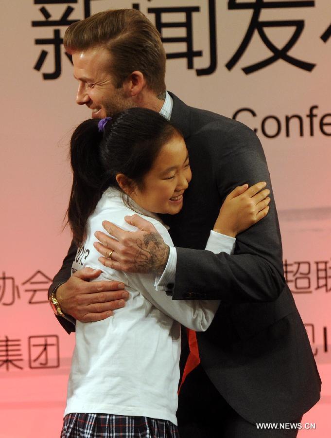 British footballer David Beckham (R) hugs a girl during a press conference in Beijing, capital of China, on March 20, 2013. David Beckham came to China as the ambassador for the youth football Program in China and the Chinese Super League (CSL). (Xinhua/Gong Lei) 