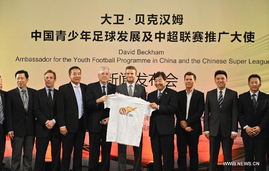 British footballer David Beckham (C) holds up a CSL souvenir T-shirt during a press conference in Beijing, capital of China, on March 20, 2013. David Beckham came to China as the ambassador for the youth football program in China and the Chinese Super League (CSL). (Xinhua/Cao Can)