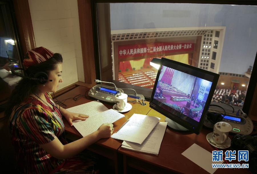 Photo shows an interpreter making simultaneous interpretation from Mandarin to Uygur language at the opening of the first session of the 12th NPC National Committee. (Photo/ Xinhua)