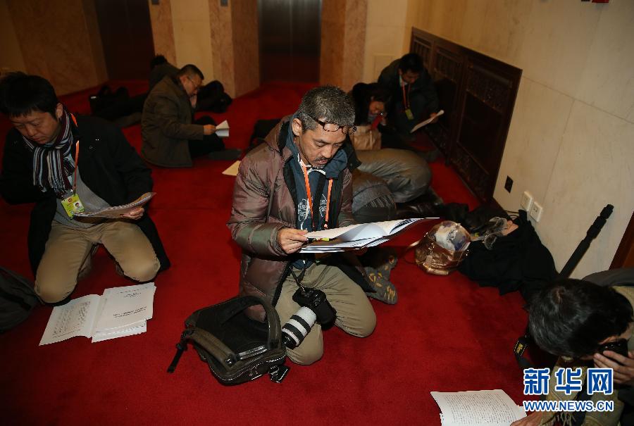 Journalists are reading the documents of the first session of the 12th NPC National Committee carefully on March 5. (Photo/ Xinhua)