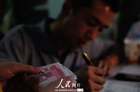 Li calculates the daily turnover and expenditures when restaurant closes at night. The 300 yuan in Li's hand is almost the revenue of three-day operations.(photo/vip.peolpe.com.cn)