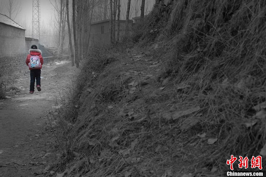 For fear of being late, Song walks to school with short quick steps on the muddy and slippery path to the school after snow. The school is about 500 meters away from the village she lives in. (Chinanews.com / Zhou Panpan)