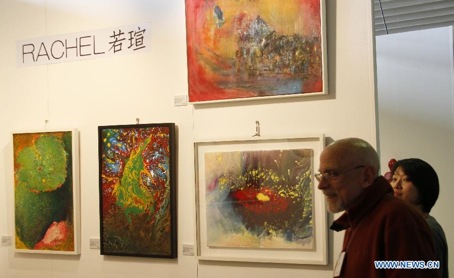 Visitors watch artworks by Chinese artist Rachel in New York City, the United States, on March 21, 2013, during the New York Art Expo which is the world's largest fine art trade show for 35 years. (Xinhua/Wang Chengyun) 