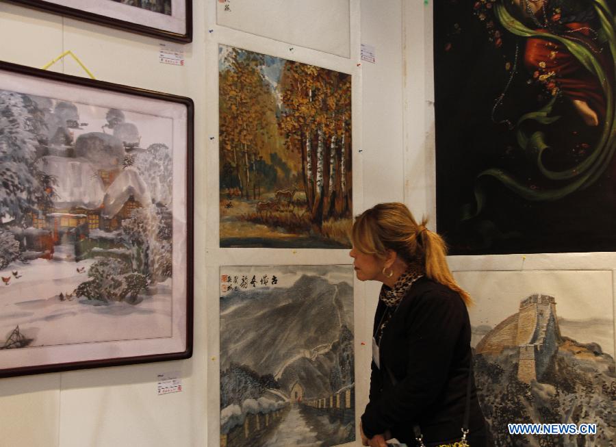 A visitor watches artworks by Chinese artists in New York City, the United States, on March 21, 2013, during the New York Art Expo which is the world's largest fine art trade show for 35 years. (Xinhua/Wang Chengyun) 