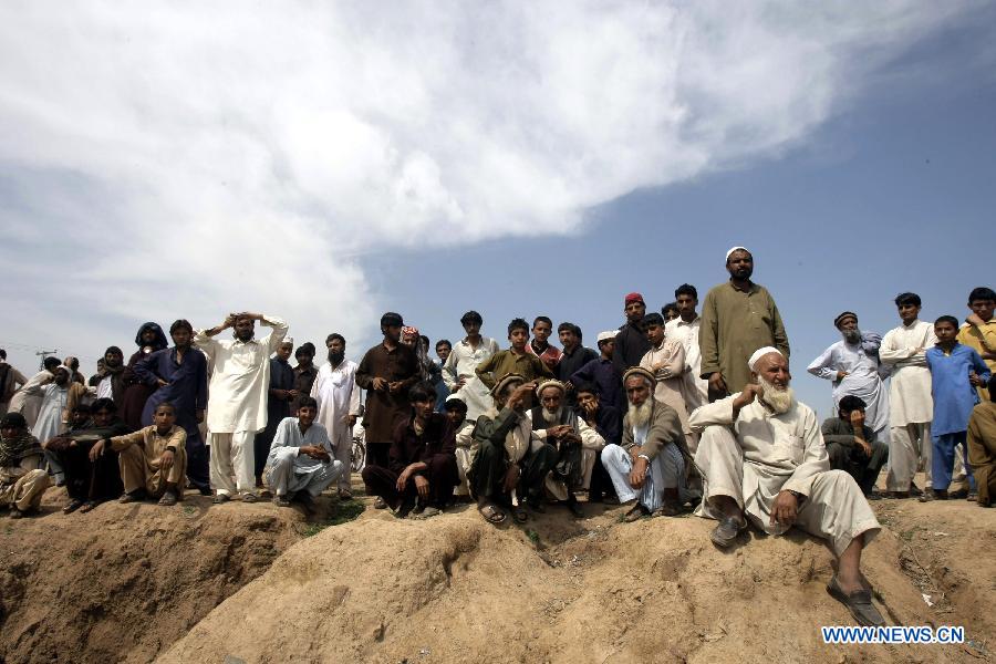 Local residents gather at the site of a bomb attack at the Jalozai refugee camp in northwest Pakistan's Nowshera on March 21, 2013. At least 12 people were killed and 35 others injured when a bomb hit a refugee camp in Nowshera on Thursday morning, local officials said. (Xinhua Photo/Umar Qayyum)