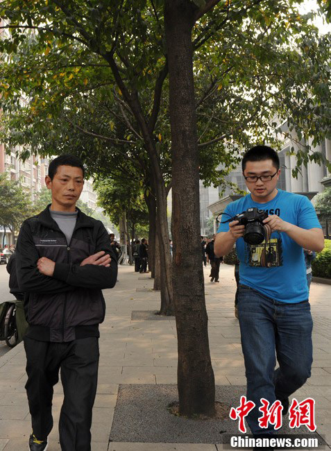 A reporter follows Zhang Guiying’s relative who just steps out of the court.  Zhang, girlfriend of serial homicidal thief Zhou Kehua, was sentenced to five years in jail on Friday by a court in southwest China's Chongqing Municipality. (Chinanews.com/Chen Chao) 