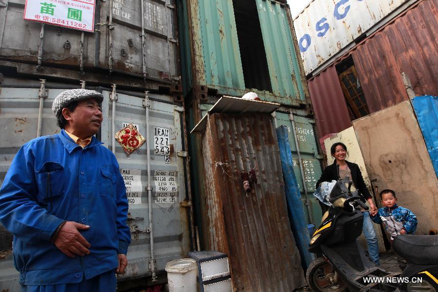 Landlord Zhang Baofa (L) introduces his container apartments in Sanlin Town in suburban Shanghai, east China, March 22, 2013. With a monthly rent of 500 yuan (about 80 U.S. dollars) for each container, three migrant worker families settled into their low-cost homes converted from abandoned containers in the metropolis. (Xinhua/Pei Xin)