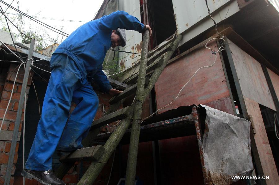 Landlord Zhang Baofa climbs into his container apartment in Sanlin Town in suburban Shanghai, east China, March 22, 2013. With a monthly rent of 500 yuan (about 80 U.S. dollars) for each container, three migrant worker families settled into their low-cost homes converted from abandoned containers in the metropolis. (Xinhua/Pei Xin)  