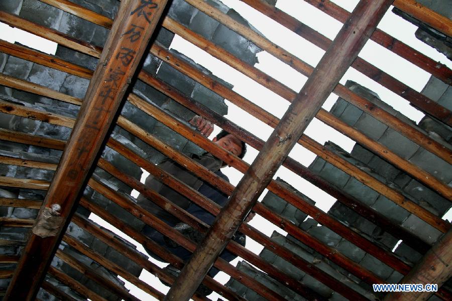 Villager Wan Xianhong repairs his roof at Shuangxi Village of Shuangxi Township in Jing'an County, east China's Jiangxi Province, March 23, 2013. Heavy rainfall and hailstorm battered the county Friday, causing severe waterlogging. In the havoc, gales and hailstorms damaged 5,700 houses, affecting more than 26,780 people.(Xinhua/Xu Zhongting) 