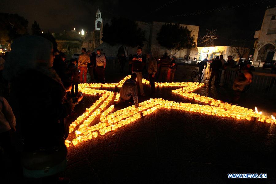 Palestinians gather around candles to mark the "Earth Hour" near the Church of Nativity in the West Bank city of Bethlehem on March 23, 2013. (Xinhua/Luay Sababa) 