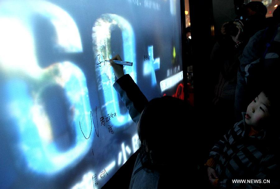 Children sign their names while attending the "Earth Hour" event in Shanghai, east China, March 23, 2013. (Xinhua/Chen Fei)