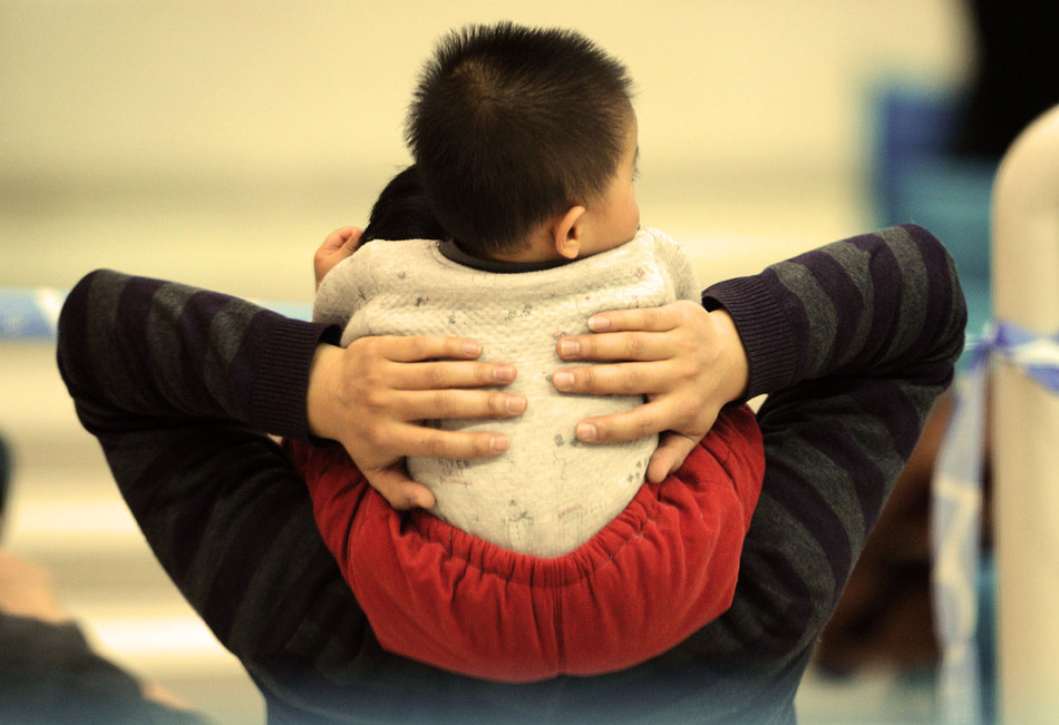 A toddler sits on father’s shoulders as they watch the FINA Diving World Series 2013 held at the Aquatics Center in Beijing, March 16, 2013. (Xinhua/Tao Xiyi)