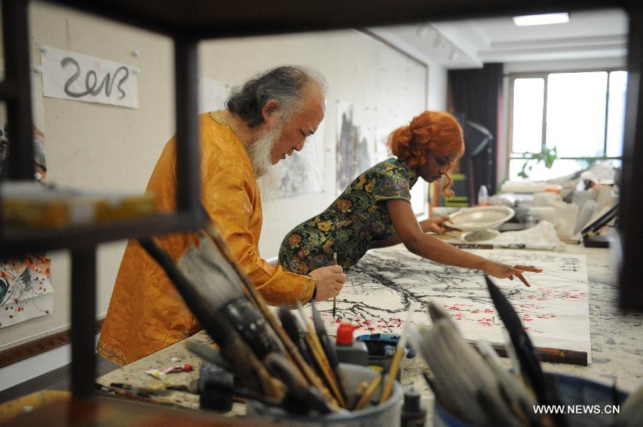 Aida Yang and her husband Yang Yan create a Chinese painting in their studio in Beijing, capital of China, March 7, 2013.(Xinhua/Zhang Ruiqi) 