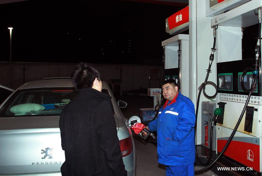 A staff member (L) refuels a car at a gas station in Nanjing, capital of east China's Jiangsu Province, March 27, 2013. China cut the retail prices of gasoline by 310 yuan (49.43 U.S. dollars) per tonne and diesel by 300 yuan per tonne starting Wednesday. The National Development and Reform Commission (NDRC) also announced a new pricing system which will adjust the prices of oil products every 10 working days to better reflect changes in the global oil market. (Xinhua/Shen Peng)