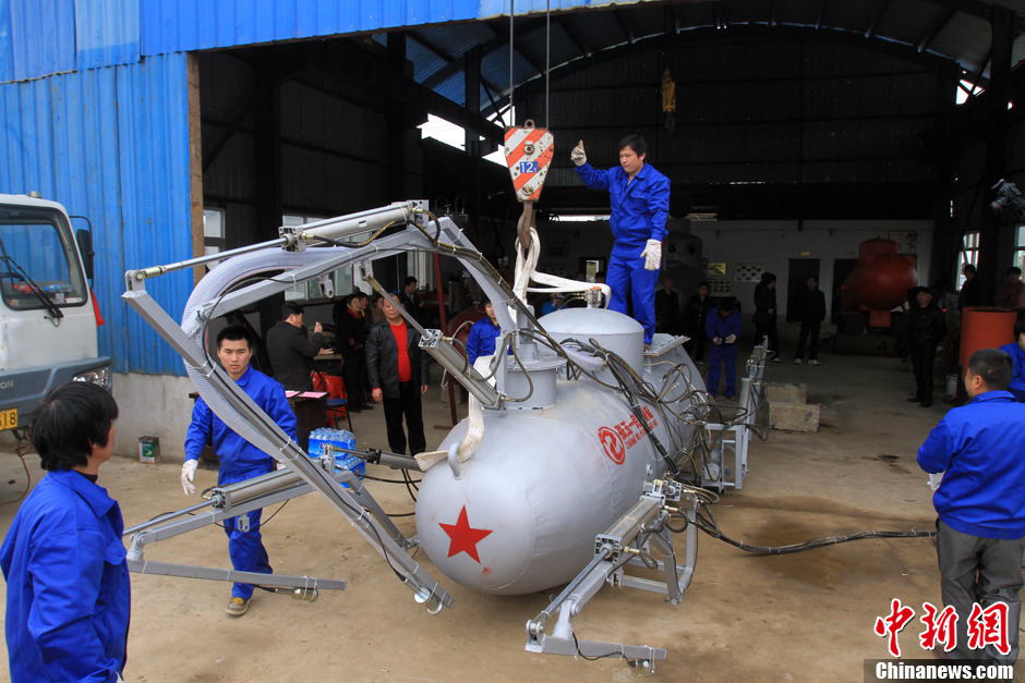 Zhang Wuyi gives instructions to his co-workers to move the newly developed unmanned underwater fishing device out of the workshop for an underwater testing in Wuhan on March 26, 2013. The “civil submarine” is equipped with a remote control and a camera for picking up image underwater. (Photo by Zhang Chang/ Chinanews.com)