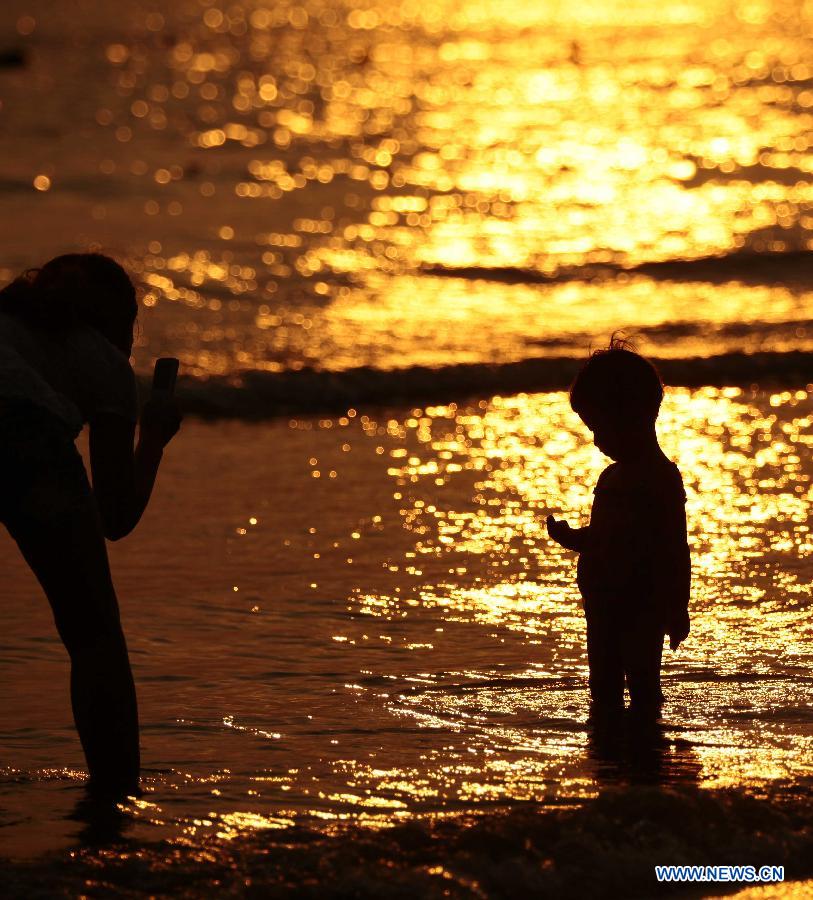 Visitors enjoy themselves on the seashore in Sanya City, south China's Hainan Province, March 27, 2013. (Xinhua/Chen Wenwu) 