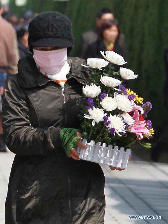 A woman carrying flowers enters the Binhaiguyuan cemetery in east China's Shanghai Municipality, March 28, 2013. As the Chinese traditional Qingming Festival, or Tomb-sweeping Day, which falls on April 4 this year, is drawing near, cemetries in Shanghai began to experience a pre-festival peak. (Xinhua/Ding Ting) 