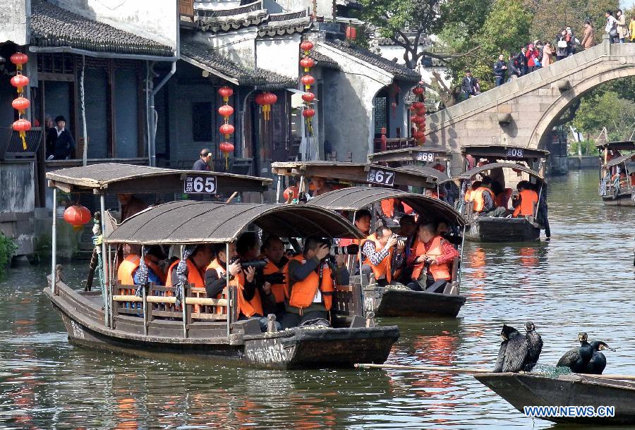 Visitors take boats while touring in the Xitang Township of Jiaxing City in east China's Zhejiang Province, March 30, 2013. Xitang, a township which enjoys thousand years' history, embraced large numbers of visitors recently. (Xinhua/Wang Song)