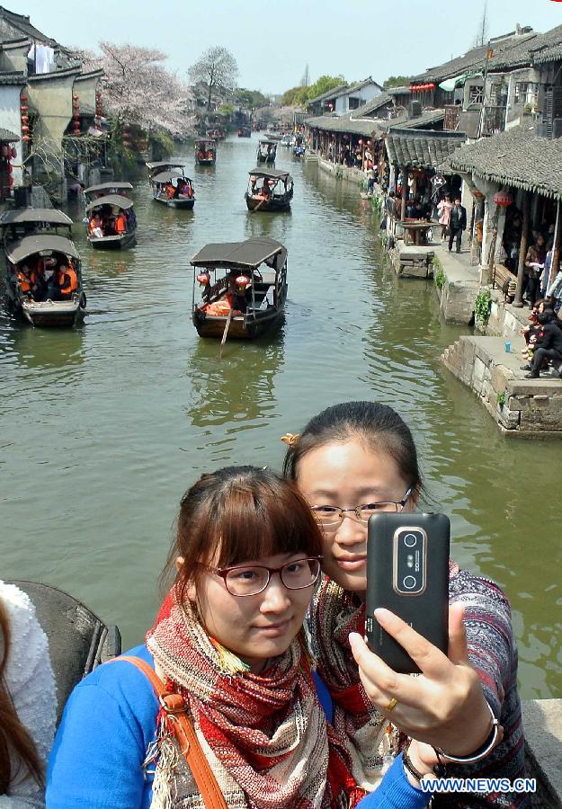 Two girls take photos of themselves in the Xitang Township of Jiaxing City in east China's Zhejiang Province, March 30, 2013. Xitang, a township which enjoys thousand years' history, embraced large numbers of visitors recently. (Xinhua/Wang Song)
