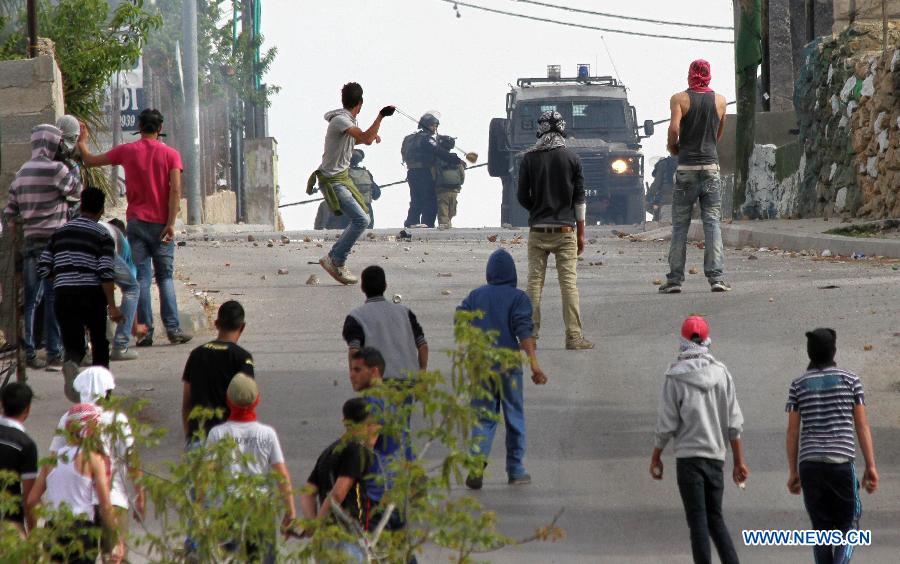 Palestinians hurl stones toward Israeli soldiers during clashes in the West Bank village of Al-Khader near Bethlehem on March 30, 2013. Riots broke out Saturday across the West Bank on the Palestinian Land Day, leaving two Israeli soldiers and one Israeli toddler lightly wounded. (Xinhua/Luay Sababa)