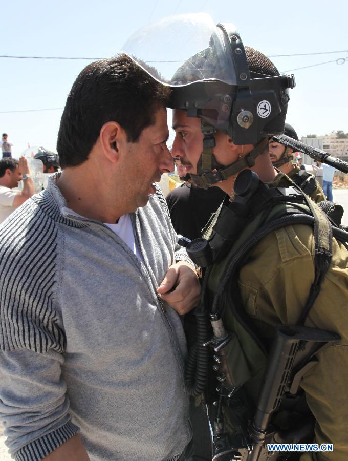 A Palestinian protester(L) confronts an Israeli soldier during a demonstration against Israel's controversial separation barrier in the West Bank village of Al-Maasarah, near Bethlehem, March 29, 2013.(Xinhua/Luay Sababa)