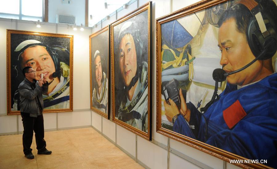 A visitor takes photo of pictures presented during the China's Space Exhibition in Hebei Museum in Shijiazhuang, capital of north China's Hebei Province, April 1, 2013. The exhibition which will last till April 7 included the display of space carriers, rocket-launcher models of the Long March series, paintings and photos related to aerospace. (Xinhua/Wang Xiao) 