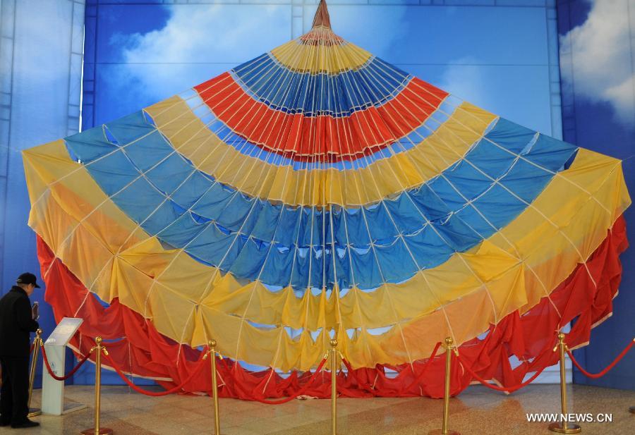 A visitor looks at a parachute presented during the China's Space Exhibition in Hebei Museum in Shijiazhuang, capital of north China's Hebei Province, April 1, 2013. The exhibition which will last till April 7 included the display of space carriers, rocket-launcher models of the Long March series, paintings and photos related to aerospace. (Xinhua/Wang Xiao) 