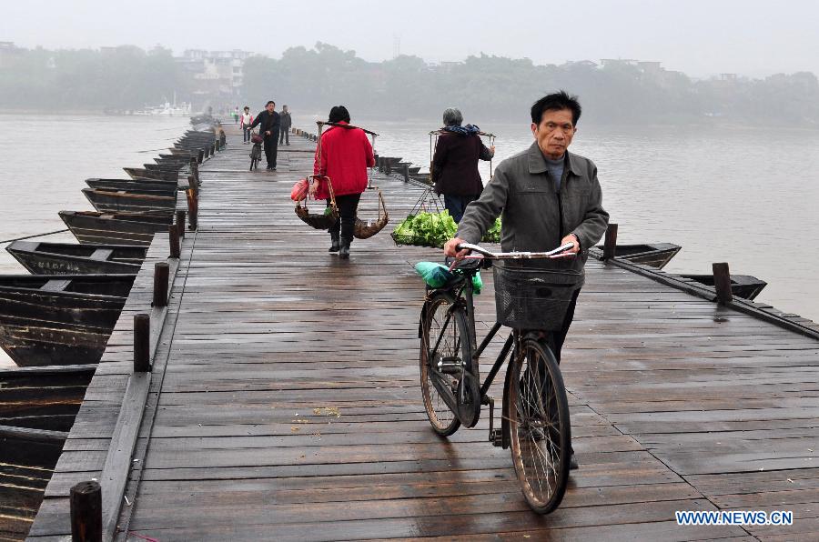 People walk on an ancient floating bridge across the Gongjiang River in Ganzhou, east China's Jiangxi Province, April 1, 2013. The wooden bridge, running 400 meters, is supported by some 100 floating boats anchored in a row. The bridge could date back to the time between 1163 and 1173 during the Song Dynasty, and has become a scene spot of the city. (Xinhua)