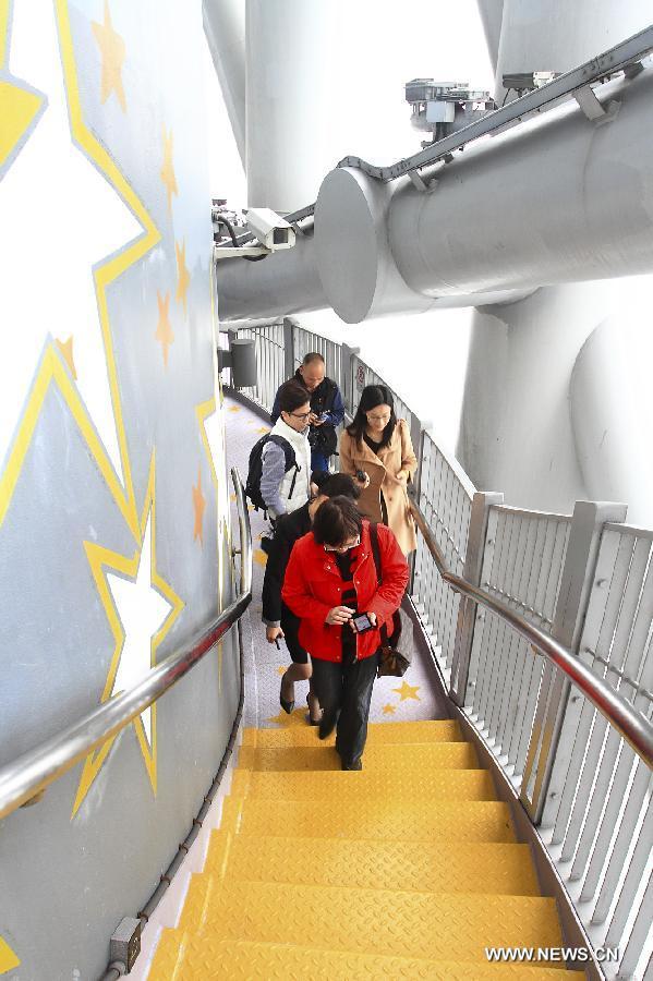 Visitors walk along the Spider Walk in the Canton Tower in Guangzhou, capital of south China's Guangdong Province, April 2, 2013. The 1,000-meter-long Spider Walk locates at the 168-meter to 334.4-meter height of Canton Tower, with a transparent floor made up of 90 pieces of glasses. Visitors would get a general view of the scenery of Guangzhou City from the Spider Walk. (Xinhua/Shen Dunwen)