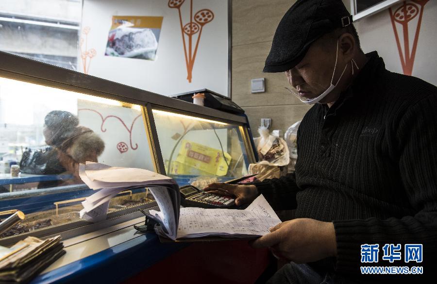 Qi Fayi checks the accounts in his snack shop. (Xinhua Photo/ Wang Fei) 