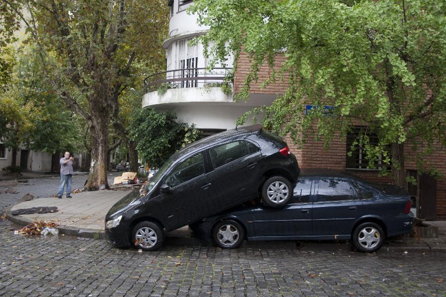 A resident takes pictures of two vehicles after a storm hit the city of Buenos Aires, capital of Argentina, on April 2, 2013. (Xinhua/Matín Zabala)  