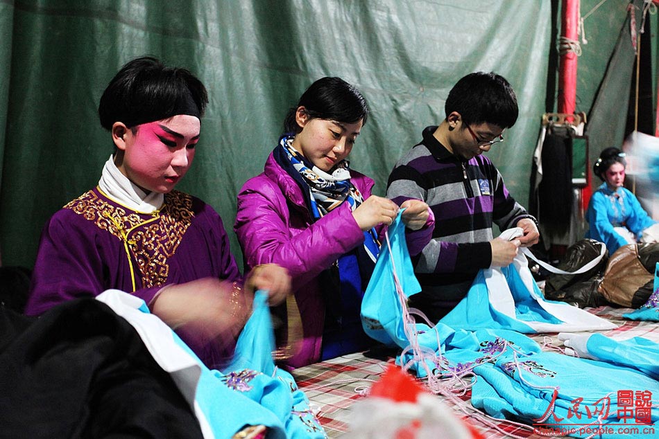 Yang Xiayun works with other troupe members to alter the costumes. 