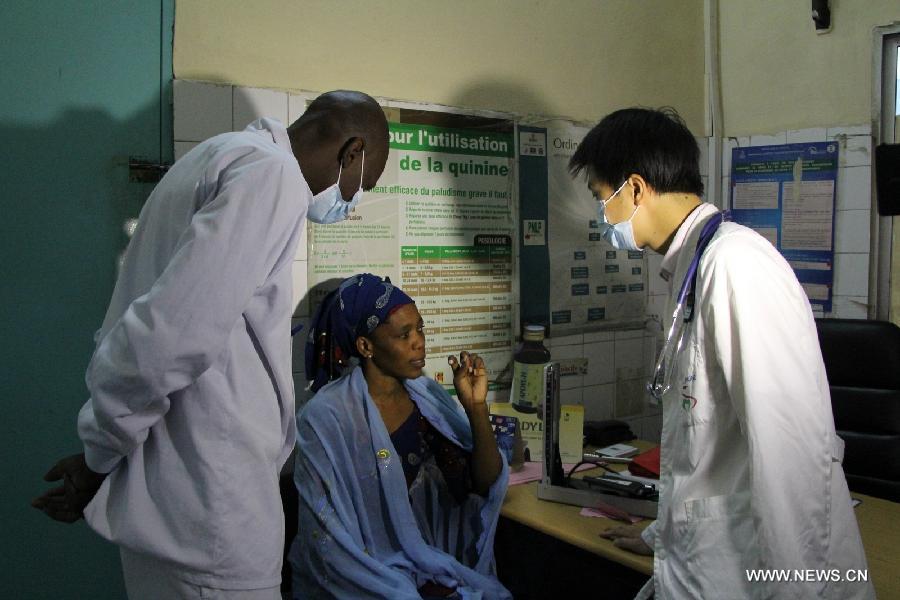 A Chinese doctor (R) asks a female patient about her symptoms, with the help of his Senegalese peer (L), at the Hann/Mer Medical Center in Darkar, capital of Senegal, March 31, 2013. The 14th Chinese medical team in Senegal provided free medical service and medication to local people in Dakar on March 31. (Xinhua/Wang Meng)