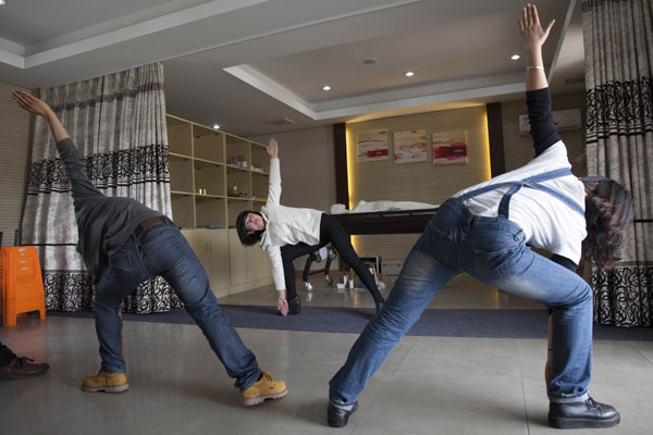 Each day before starting work, they will gather for yoga exercise. [Photo by Gao Erqiang / China Daily]