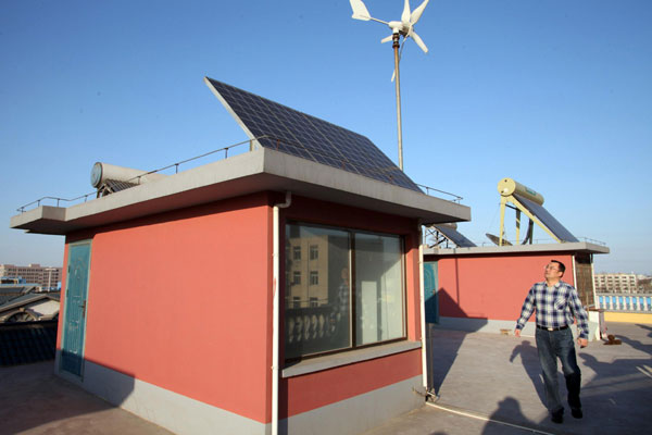 Dong Qiang stands beside an electricity generator panel on his roof in Tianjin on April 6, 2013. The Tianjin Binhai Electricity Company, a branch of the State Grid, recently received from Dong the first individual application to sell electricity. Dong said the electricity generated by his panels can be used for his home while remaining electricity can be sold. (Photo/Xinhua)