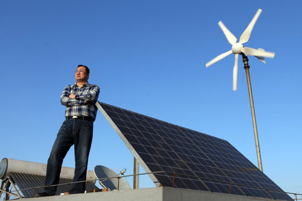 Dong Qiang, who applied to sell independently generated electricity in Tianjin, inspects the solar and wind panel grids on his roof in Tianjin on April 6, 2013. The Tianjin Binhai Electricity Company, a branch of the State Grid, recently received from Dong the first individual application to sell electricity. Dong said the electricity generated by his panels can be used for his home while remaining electricity can be sold. (Photo/Xinhua)