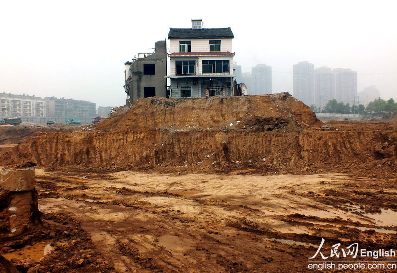 A "nail house" remains standing at a construction site in Gongqin village of Yichang city, Central China's Hubei province, April 8, 2013. A nail house is a Chinese term for homes whose owners refuse to move to make room for property development. Usually the homeowners can't come to an agreement with developers about compensation. Over the past year, power and water supplies to this house were repeatedly cut off in anonymous attacks at night. [Photo/CFP]