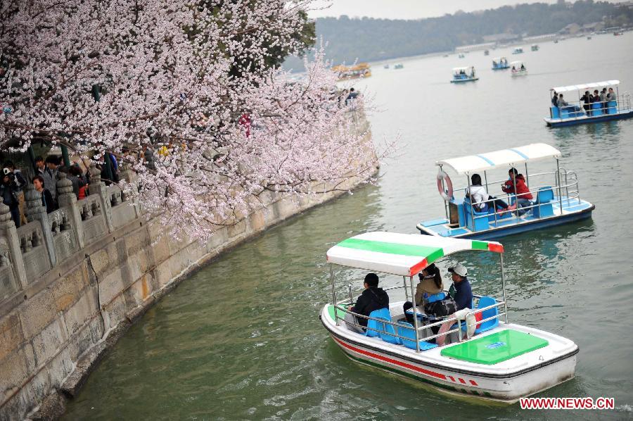 Visitors view peach flowers on boats at the Summer Palace in Beijing, capital of China, April 4, 2013. (Xinhua/Chen Yehua)