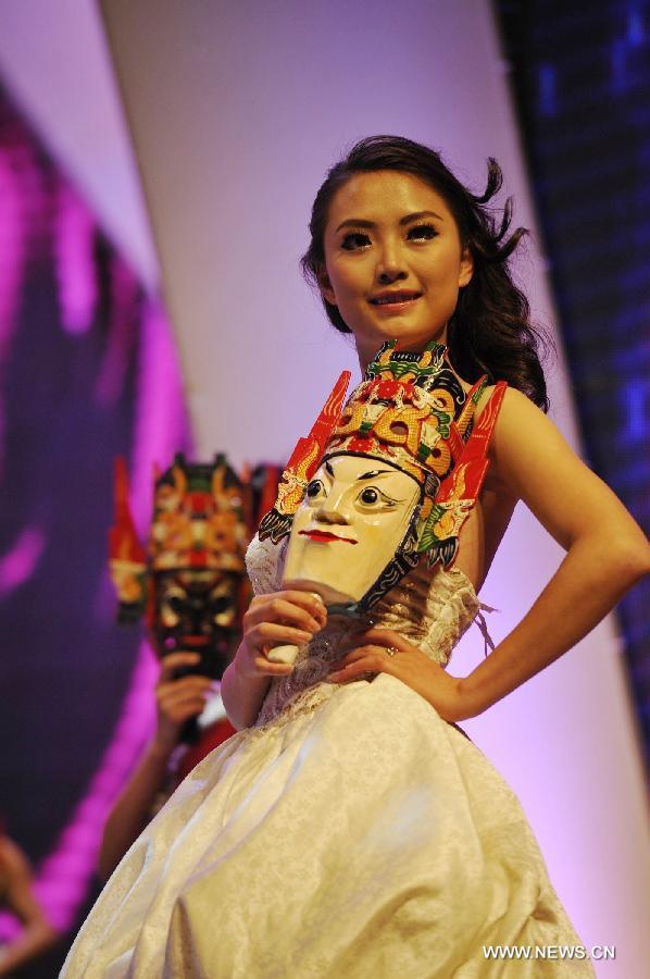 A competitor shows a mask of Nuoxi, a local performing art, during the final match of the 2013 Miss Tourism International (Guizhou) in Guiyang, capital of southwest China's Guizhou Province, April 9, 2013. The final match, with the participation of 31 competitors, closed here Tuesday. (Xinhua/Ou Dongqu)