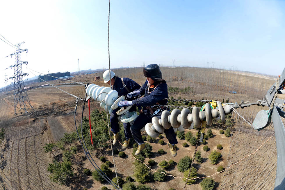 Maintainers examine the 220 KV transmission line in Beidaihe to guarantee electric safety for agricultural production on March 29, 2013. (Xinhua Photo/ Yang Shirao)
