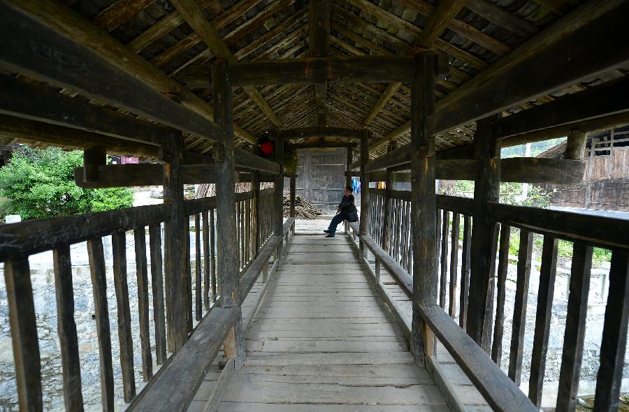 A villager rests on a bridge in Lianghekou Village in Enshi, central China's Hubei Province, April 10, 2013. Stilted buildings of Tujia ethnic group, mainly seen in central China's Hunan and Hubei Province, is a gem of Chinese residence. Lianghekou Village is one of the best reserved areas for Tujia stilted buildings. (Xinhua/Song Wen)