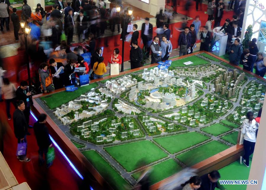 People stand around a sand table of a property project at Beijing Spring Real Estate Trade Fair in Beijing, capital of China, April 11, 2013. The four-day fair kicked off on Thursday. (Xinhua/Gong Lei)