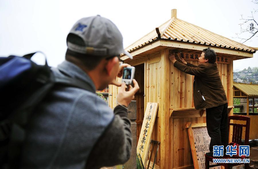 A worker installs signs for admission fees at a ticket window in Fenghuang, an old town that draws many visitors for its natural landscapes, in Hunan, April 9, 2013. (Xinhua/Zhao Zhongzhi)