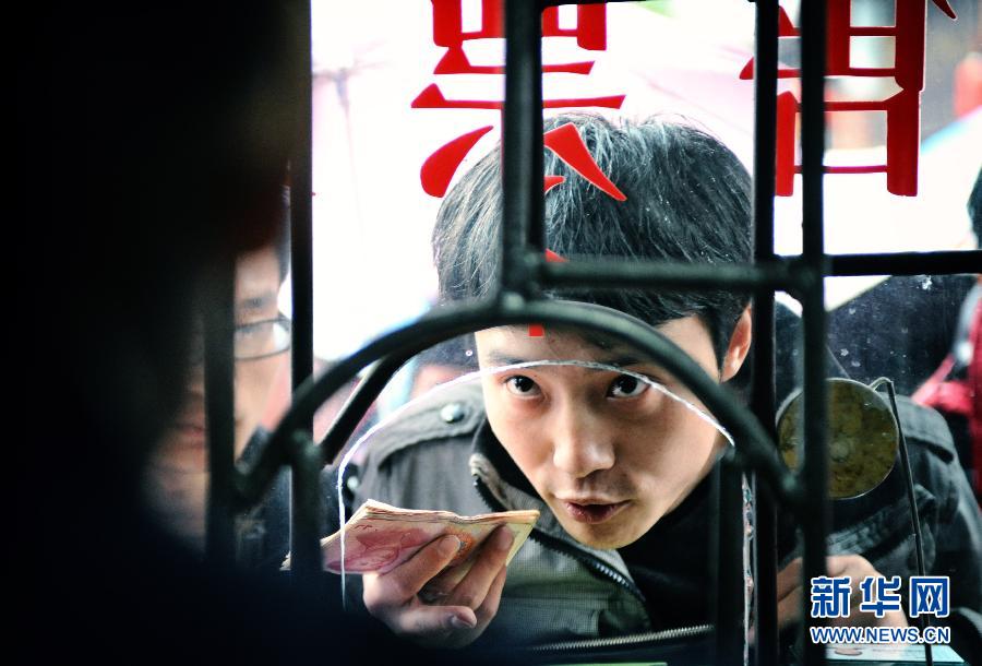 A tourist guide buys tickets at an entrance to Fenghuang, an ancient town in central China's Hunan province, April 10, 2013. (Xinhua/Cheng Tingting)