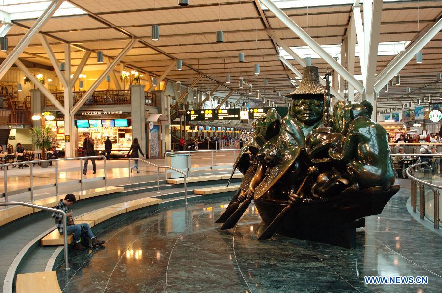 A boy sits beside a sculpture entitled "The Spirit of Haida Gwaii" by renowned Canadian artist and carver Bill Reid at Vancouver International Airport (YVR) in Vancouver, Canada, April 10, 2013. YVR was named Best Airport in North America at the Skytrax World Airport Awards in Geneva, Switzerland on April 10. YVR is rated 8th overall worldwide and is the only North American airport included in the top ten. (Xinhua/Sergei Bachlakov) 
